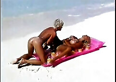 Busty nude blonde relaxing on the beach with her friend